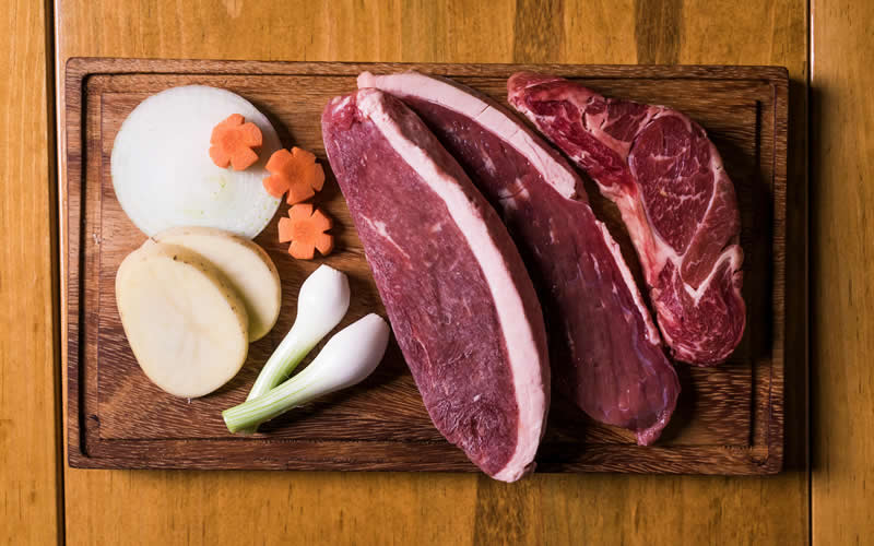carne-e-verduras-sobre-a-mesa Peças de carnes frescas sobre a tábua acompanhada de algumas verduras