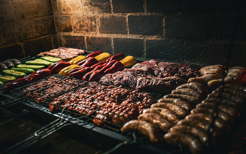 churrasqueira-de-tijolo Churrasqueira ampla de tijolos em uso com carnes e vegetais sendo assados