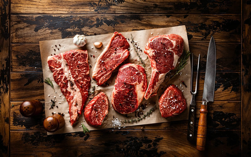 Diversos tipos de carne vermelha prontas para assar sobre a mesa
